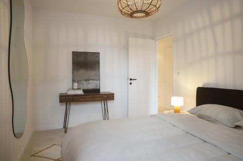 ein weißes Schlafzimmer mit einem Bett und einem Tisch in der Unterkunft Luxe appartement in Antwerpen in Antwerpen