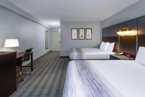 a hotel room with two beds and a desk at AmericInn by Wyndham Peoria in Peoria