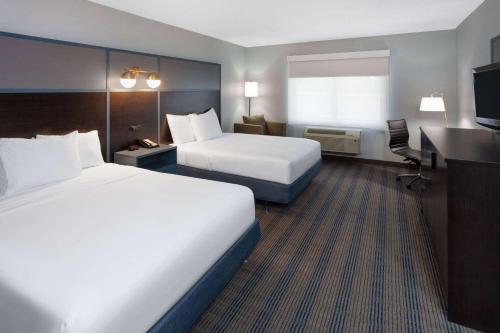 a hotel room with two beds and a desk at AmericInn by Wyndham Peoria in Peoria