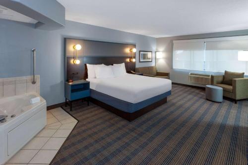 um quarto de hotel com uma cama e uma banheira em AmericInn by Wyndham Peoria em Peoria