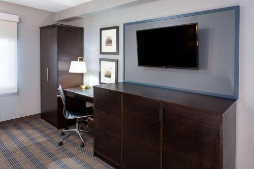 a hotel room with a desk and a flat screen tv at AmericInn by Wyndham Peoria in Peoria