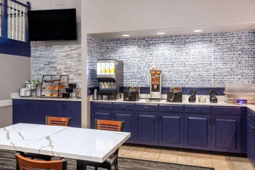 a kitchen with blue cabinets and a white table at AmericInn by Wyndham Peoria in Peoria