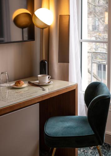 Cette chambre comprend un bureau avec une chaise et une lampe. dans l'établissement Hôtel Le Tourville by Inwood Hotels, à Paris
