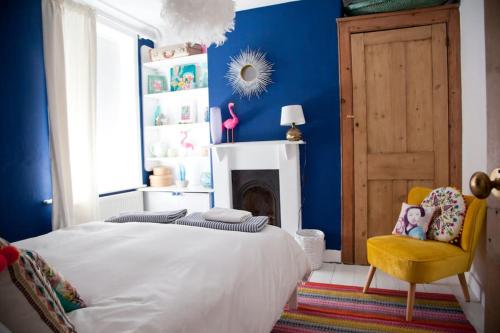 een slaapkamer met blauwe muren en een bed en een stoel bij Whitstable Cottage - Perfect Location in Whitstable