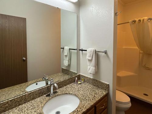 Motel 6 Portland, IN في Portland: حمام مع حوض ومرحاض ومرآة