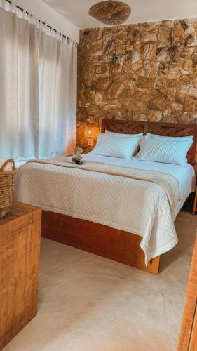 a bedroom with a large bed with a stone wall at Saona Bangalôs Taíba in Taíba