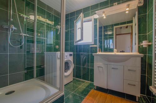 baño de azulejos verdes con ducha y lavamanos en Les epervieres, en Lentilles