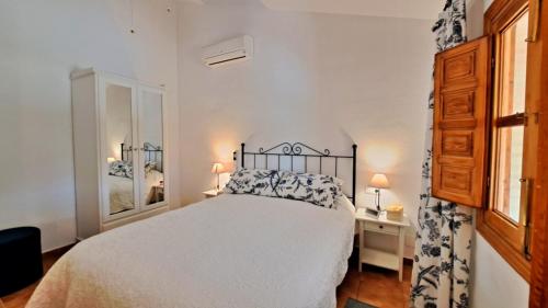 1 dormitorio con 1 cama, 2 mesas y 2 lámparas en La Perla Andaluza, en Alcaucín