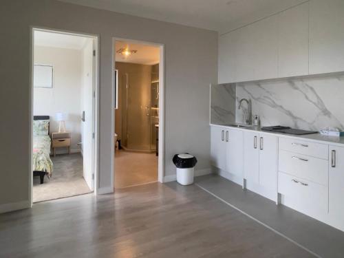 a kitchen with white cabinets and a living room at Murphys Guest Home in Auckland