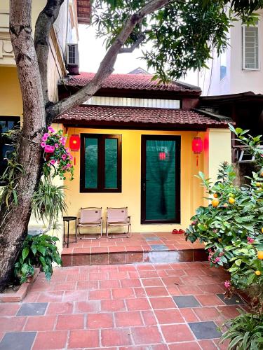 a yellow house with two chairs on a brick patio at Lee Homestay in Hanoi