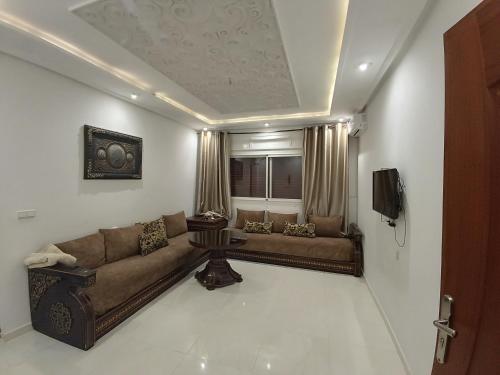 a living room with a couch and a television at Furnished apartments Family only in Tangier