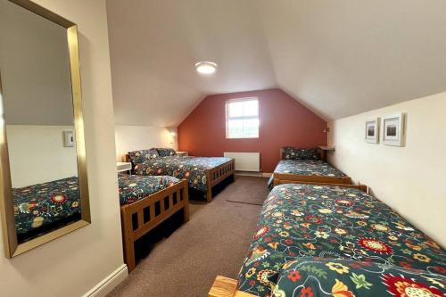 a attic room with three beds and a mirror at Into The Burren in Murroogh