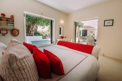 um quarto com uma cama branca e almofadas vermelhas em Rothersands 16 em Plettenberg Bay