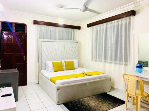 ein Schlafzimmer mit einem Bett mit gelben Kissen und einem Schreibtisch in der Unterkunft D15 in Mombasa