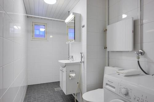 Baño blanco con aseo y lavamanos en Kotimaailma- Valoisa kaksio jopa viidelle en Helsinki