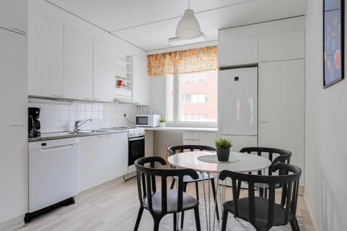 een keuken met een tafel en stoelen bij Kotimaailma- Valoisa kaksio jopa viidelle in Helsinki