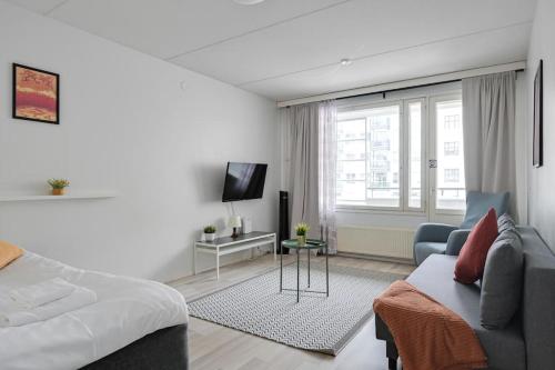 ein Wohnzimmer mit einem Bett, einem Sofa und einem TV in der Unterkunft Kotimaailma- Valoisa kaksio jopa viidelle in Helsinki