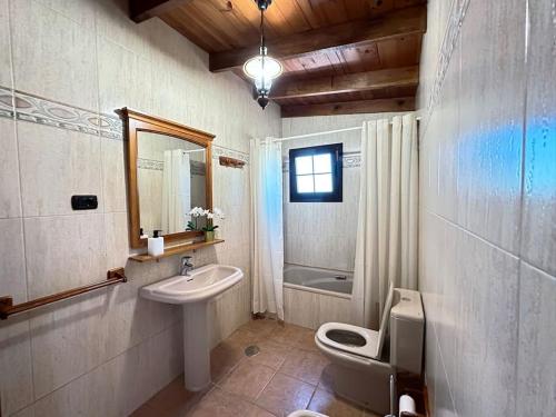 a bathroom with a sink and a toilet and a mirror at Cómoda villa en la montaña in Gran Tarajal