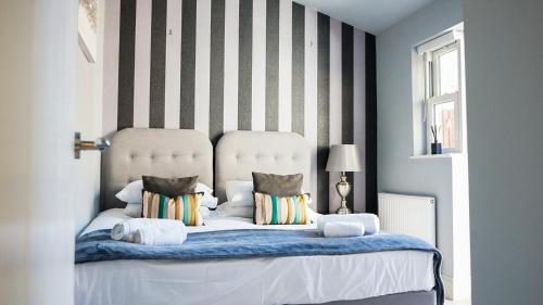 - une chambre avec un grand lit blanc aux murs rayés dans l'établissement Stunning 1 bedroom apartment with courtyard - Flat 3, à Bedford