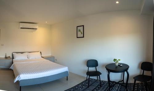 um quarto com uma cama, 2 cadeiras e uma mesa em Remedy Hostel em Vientiane