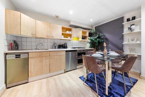 - une cuisine avec des placards en bois, une table et des chaises dans l'établissement Deluxe Apartment - 1 Min Away From Camden Market and Station, à Londres