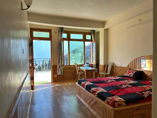 a bedroom with a bed and a table and windows at Aarav Homestay in Kalpa