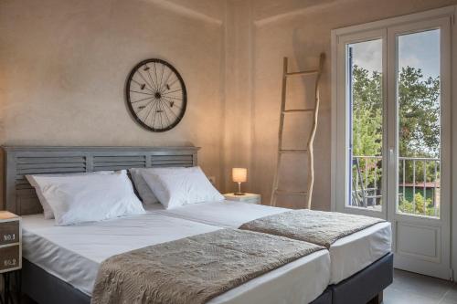 Luxurious Villa Nadoria, Ithaca Island في فاثي: غرفة نوم بسرير كبير وساعة على الحائط