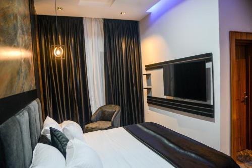 a hotel room with a bed and a television at The Kingsley - La Prima Casa in Lagos