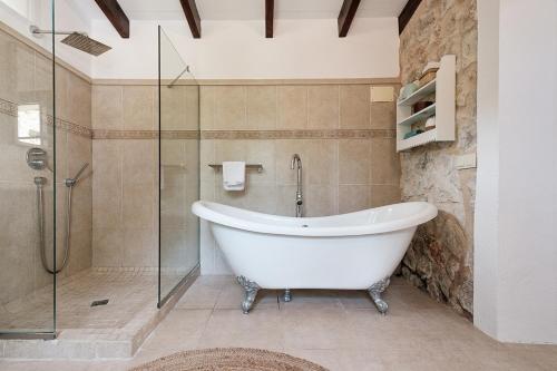 a bath tub in a bathroom with a glass shower at Villa Can Ros in Capdellá