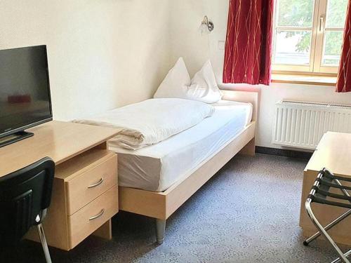 una camera con letto e scrivania con TV di Hotel Restaurant Zum Wendelwirt a Germaringen