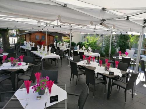 a restaurant with white tables and chairs and pink flowers at Hotel Restaurant Zum Wendelwirt in Germaringen