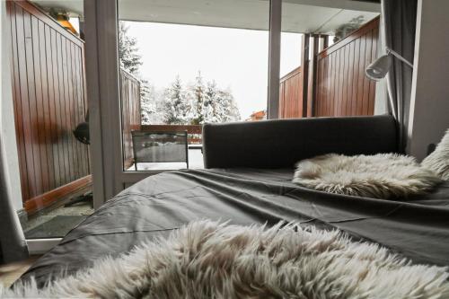 a bed with furry pillows in a room with a balcony at Joli studio avec parking gratuit in Crans-Montana