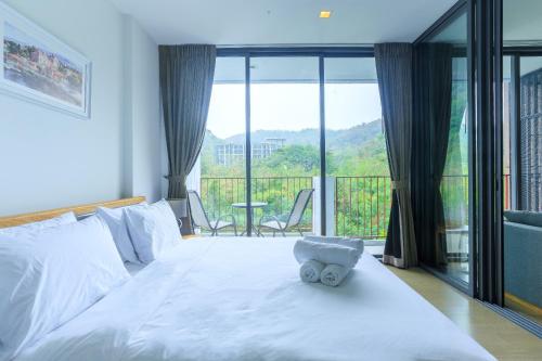 Mountain View Retreat at Khaoyai في Ban Huai Sok Noi: سرير ابيض و دبدوب يجلس عليه
