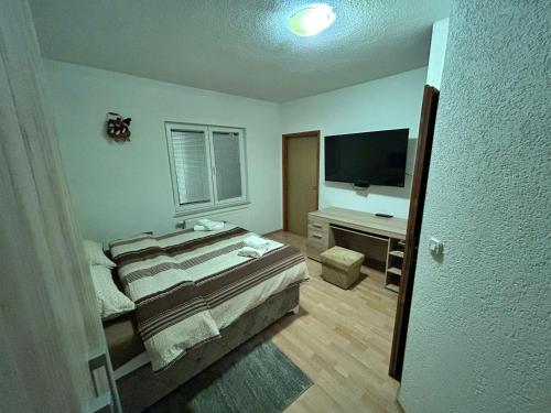 1 dormitorio con 1 cama y escritorio con TV en Apratmani Ivić, en Kupres