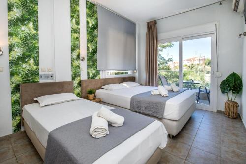 two beds in a room with a large window at Hotel Discovery Thassos in Limenaria