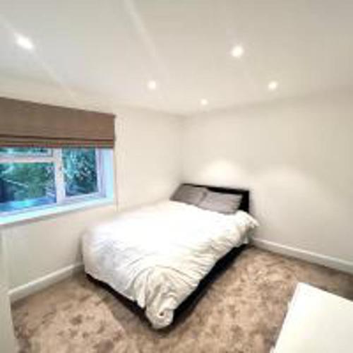 1 dormitorio con 1 cama blanca y ventana en Inviting 4-Bed House in Finchley London en Hendon