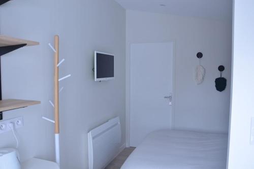 a white kitchen with a tv on the wall at Studio confortable avec terrasse privée in Le Pellerin