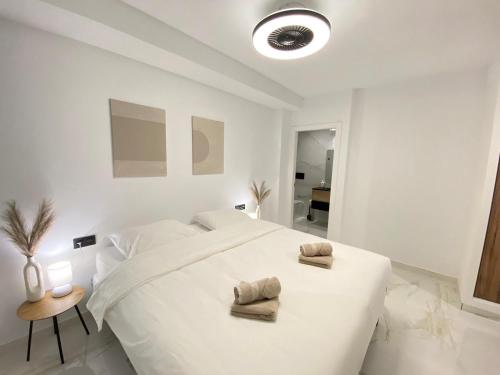 a white bedroom with a large bed with towels on it at Paseo De La Playa in Torrevieja
