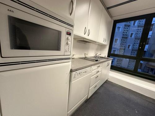 a white kitchen with a microwave and a sink at Pension Bavaria Immobilien in Nuremberg