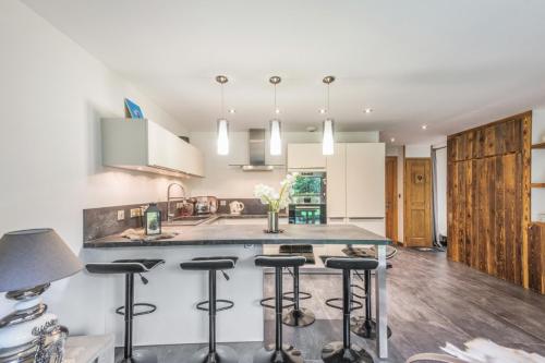 une cuisine avec un îlot et des tabourets de bar dans l'établissement Villa Princesse - Centre-ville - Renove, à Chamonix-Mont-Blanc