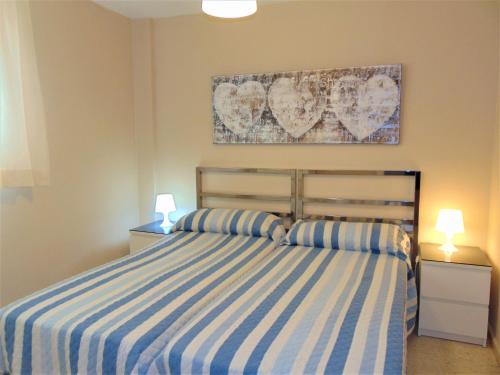1 dormitorio con 1 cama de rayas azul y blanco y 2 lámparas en Terrasol Pirámides Puerto Blanco, en Caleta de Vélez