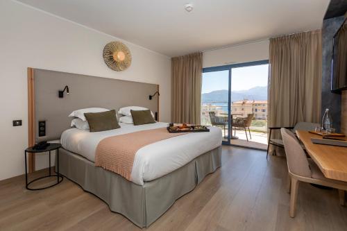 een hotelkamer met een groot bed en een bureau bij Hotel L'Acquale in Calvi