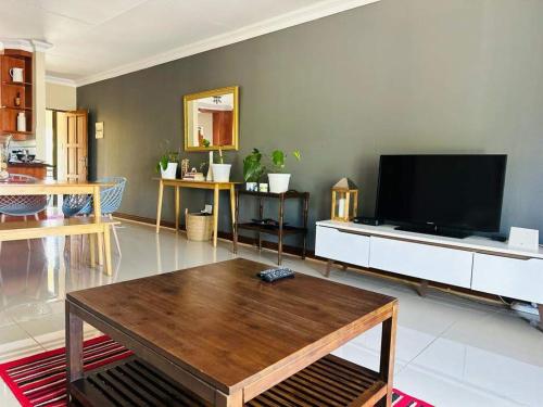 uma sala de estar com uma televisão e uma mesa de centro em 21 at Melody em Hartbeespoort