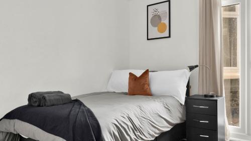 um quarto com uma cama com lençóis brancos e almofadas em 4 Bed 2 Bath House with Private Garden em Londres