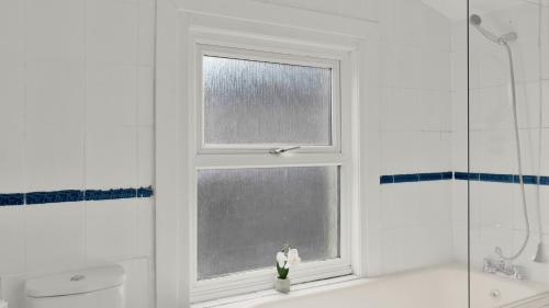 uma janela numa casa de banho com uma estatueta na banheira em 4 Bed 2 Bath House with Private Garden em Londres