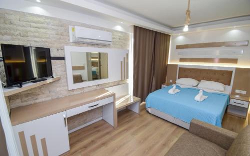 um quarto com uma cama azul e uma televisão em Esmeralda Butik Hotel em Kızılot