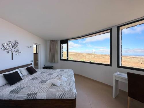 a bedroom with a bed and two large windows at Villa with views and Villaverde in Villaverde
