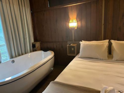 uma casa de banho com uma cama e uma banheira em Pousada Ponta da Vigia em Penha
