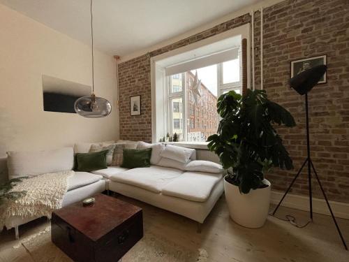 a living room with a white couch and a brick wall at ApartmentInCopenhagen Apartment 1584 in Copenhagen