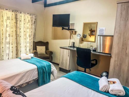a hotel room with two beds and a chair at Leribisi Lodge in Tierpoort